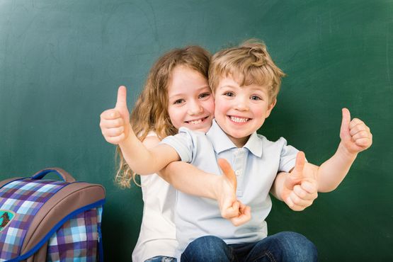 Junge Schüler zeigen mit dem Daumen nach oben